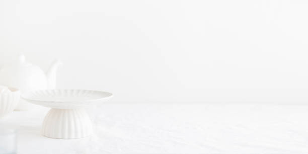 Empty tableware - white plate cakestand on white table as a background for a dessert
