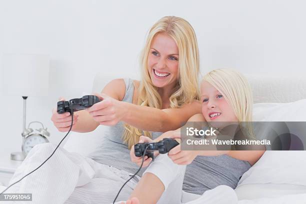 Alegre Madre E Hija Jugando Videojuegos Foto de stock y más banco de imágenes de Agarrar - Agarrar, Alegre, Almohada