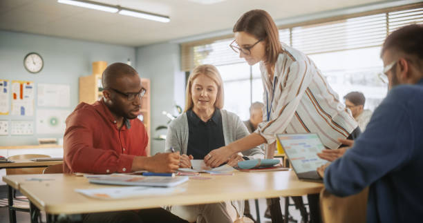 istock Grown-Up Men and Women Working in Groups for an Assignment in Specialty Development Center. Adult Classmates Working on a Team Assignment, Young Female Teacher Explaining the Exercise Goals. 1759513612