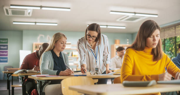 istock Helpful Young Teacher Talking with a Middle-Aged Female, Helping to Find a Solution for a Test Course Assignment. Multiethnic Women and Men of Different Age Acquiring New Academic Skills in Class. 1759515855