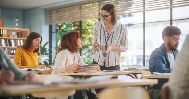 istock Young Teacher Checking Up on a Senior Female, Helping Her with a School Task, Complimenting Her Work. Modern Adult Training Center Help People to Develop New Useful Skills Throughout Life 1759527541