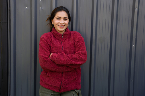 Young indian woman wearing red warm winter jacket, Standing cross arms isolated over black background