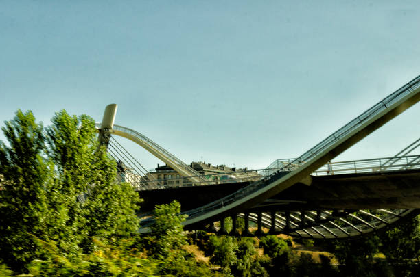 This photograph was taken on August 8, 2023 in Ourense. This is The Millennium Bridge, also known as the Gaviota Bridge due to its shape, it is one of the six bridges over the Miño River in the city of Ourense, located between the medieval bridge and the N-525 bridge. Orense is a city in Galicia known for its thermal waters, such as the Burga de Abajo, a neoclassical fountain. Nearby, the As Burgas Interpretation Center investigates the history of the city's medicinal baths. The 12th-century Ourense Cathedral houses the highly ornate Gate of Paradise. The emblematic Roman bridge, with its characteristic arches, crosses the Miño River.