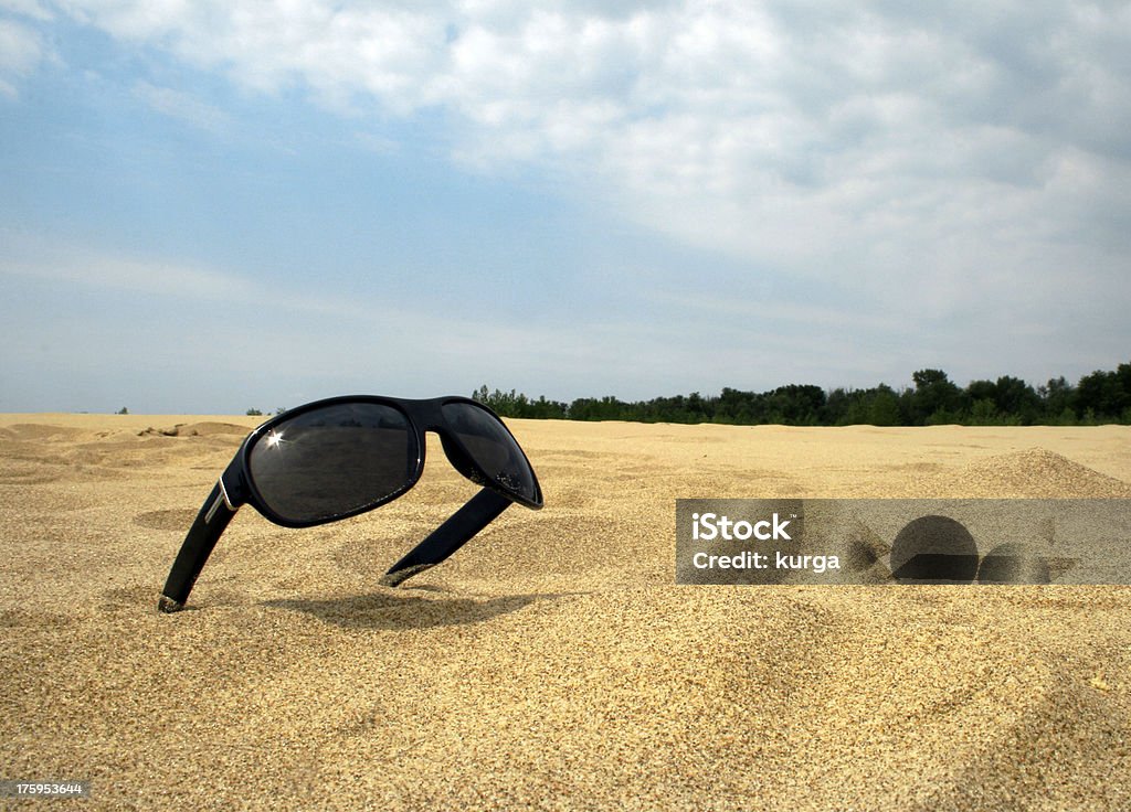 Lunettes de soleil dans une poussière d'or contre le ciel bleu - Photo de A la mode libre de droits