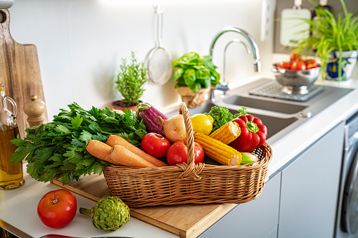 Basket full of fresh vegetables on kitchen counter