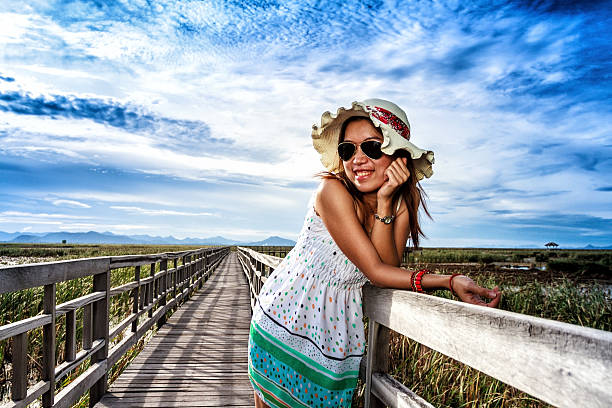 Portrait of a beautiful, young woman  wearing dotted dress, sitting on the balcony fence and eating ice cream.