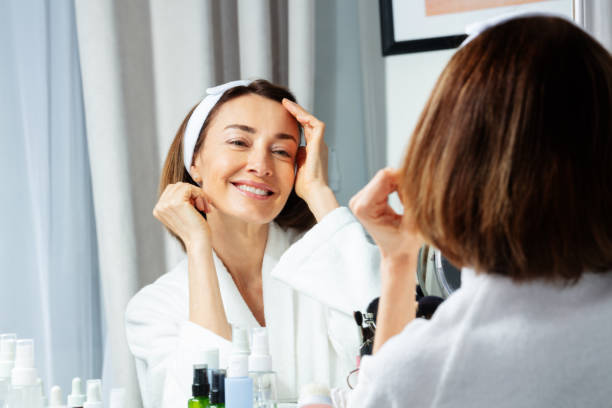 istock Smiling woman touching face wearing housecoat before mirror 1759572878