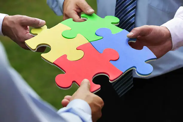 Teamwork concept, four business people holding jigsaw puzzle pieces together