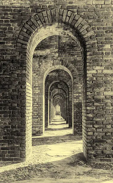 This is a vertical, monochromatic photograph of repeating brick arches in Fort Jefferson on Garden Key in the Dry Tortugas National Park.