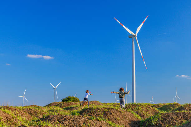 istock Children having fun on green hills by the horizontal axis wind turbines 1759605402