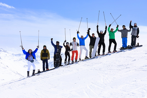Skiing and Snowboarding  club. Group of  skier and  snowboarder, male and female on the top of mountain ski slope.
