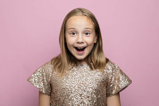 Happy excited surprised child girl against pink studio wall banner background