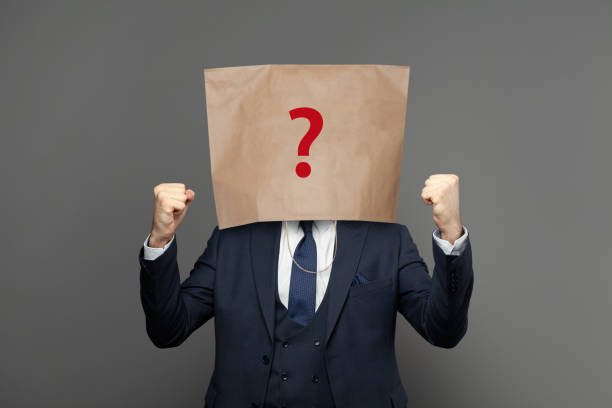 istock Corporate businessman hiding under paper bag with question mark on grey background 1759610611
