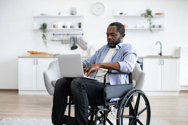 istock Man in wheelchair staying with laptop in open-plan kitchen 1759611727