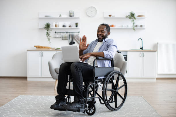 istock Man in wheelchair having video call on computer in apartment 1759612262