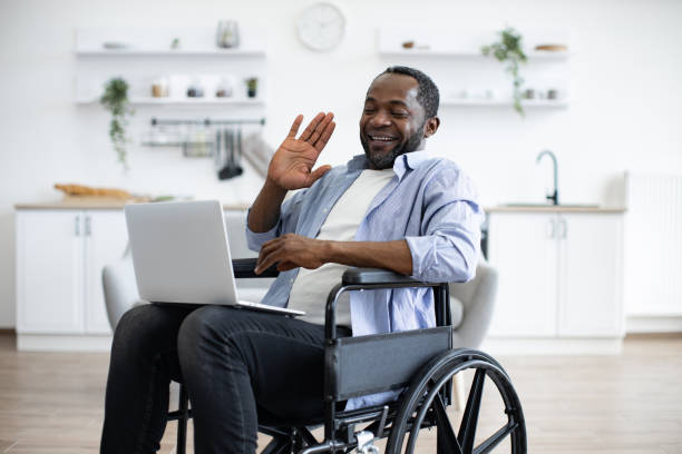 istock Man in wheelchair having video call on computer in apartment 1759612266