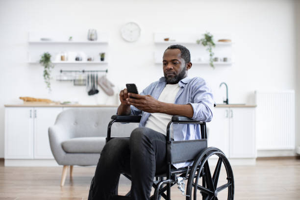 istock Male with disability texting message on phone in dining room 1759613359