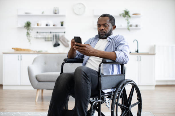 istock Male with disability texting message on phone in dining room 1759613385