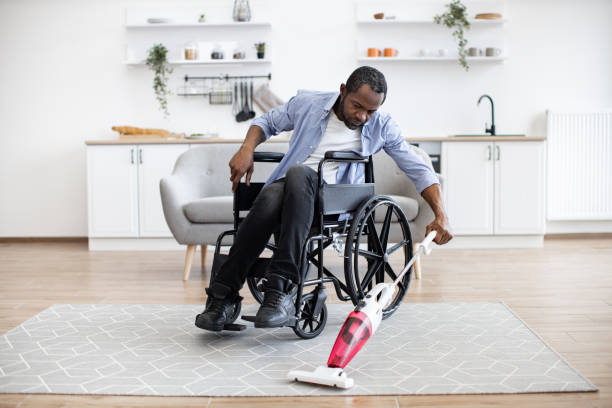istock Man with disability using cordless vacuum in apartment 1759616193