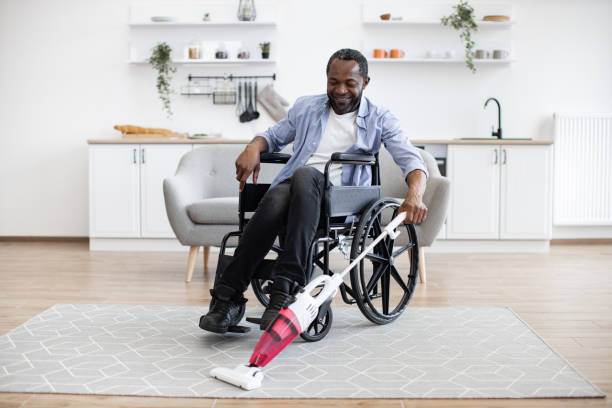 istock Man with disability using cordless vacuum in apartment 1759616701