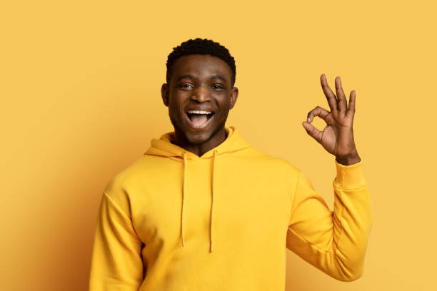 istock Cool cheerful black guy showing okay gesture on yellow 1759617233