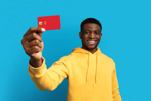 istock Happy young black guy showing bank card, blue background 1759617757