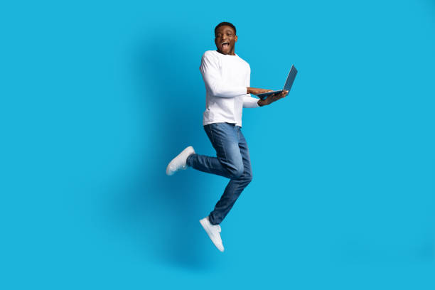 istock Happy black guy jumping with laptop in his hands 1759618834