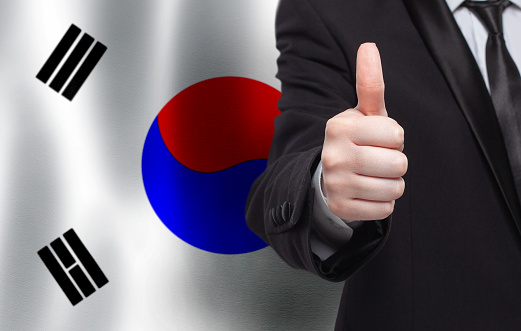 Korean concept. Businessman showing thumb up on the background of flag of Korea