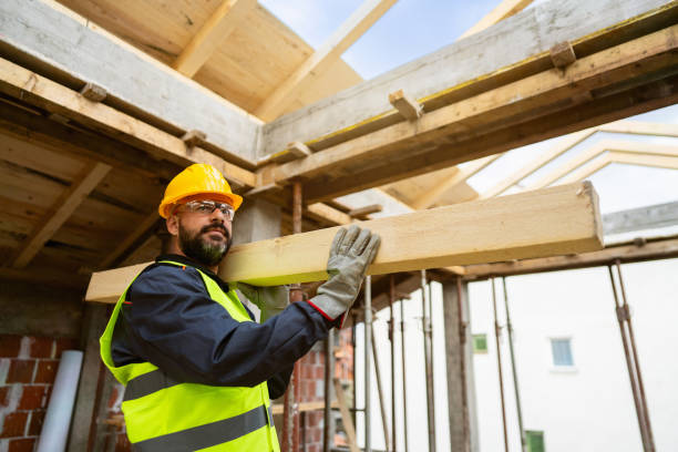 Caucasian male roofer, carrying an timber, while working on a construction site