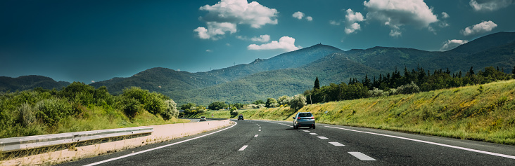 panorama Panoramic View Compact Crossover SUV In Motion On Road, Freeway, Motorway, Highway In Mountains Landscape. Drive And Travel Concept