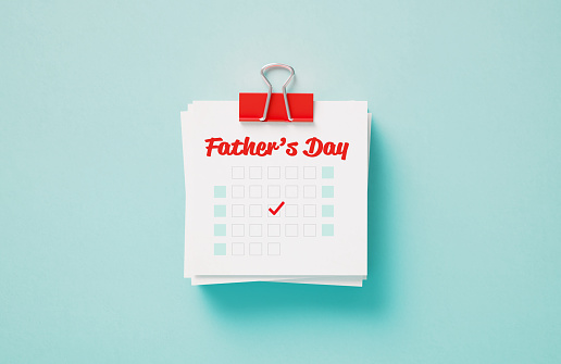 Father's Day reminder held by a red paper clip on blue background. Horizontal composition with copy space. Calendar and reminder concept.