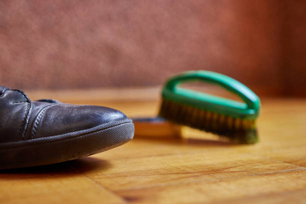 A man cleans leather shoes with a paste and a brush. Shoe care.