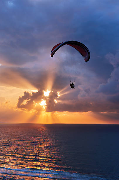 istock paragliding at sunset on sea with sun beams 175967337