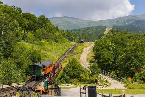 Beginning of the cog railwaytrack leading to the top of Mount Washington in New Hamsphire,  with three trains on the track