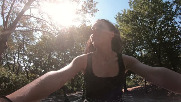 Hispanic woman with curly hair riding on a bike in Central Park. Central Park is one of the largest