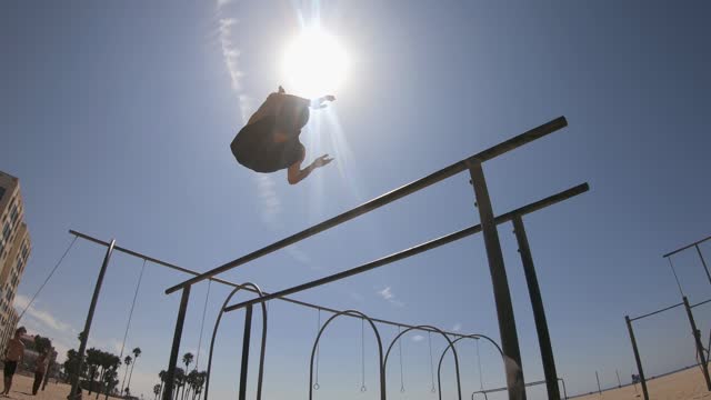 Young fit and flexible man doing gym exercises on the bars in Venice Beach, California