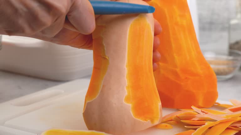 Butternut squash soup recipe. Woman hands peel and cut squash.