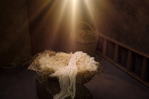 Empty crib with hay and swaddles waiting for baby Jesus on Christmas Eve