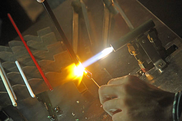 Glazier with gas torch lit while blending and shaping a piece of glass 1
