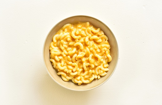 Mac and cheese in bowl over light background. Top view, flat lay