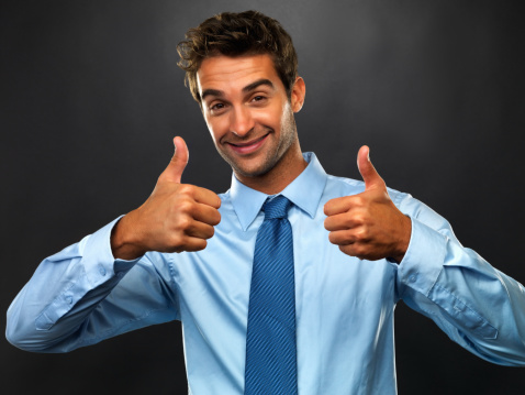 Corporate businessman smiling and giving a thumbs up, successful business concept