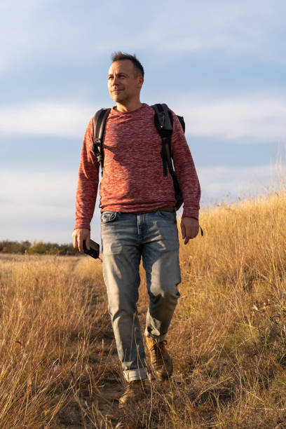 istock Young man hiking through autumn fields and hills against blue sky during warm day. Weekend, leisure, sport 1759776510