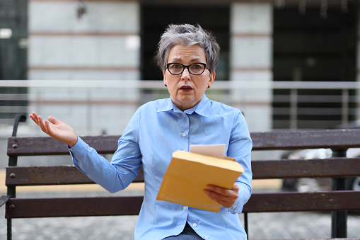 An accomplished female entrepreneur in the urban landscape, engrossed in her work and visibly perturbed, reflecting the demanding nature of the business world