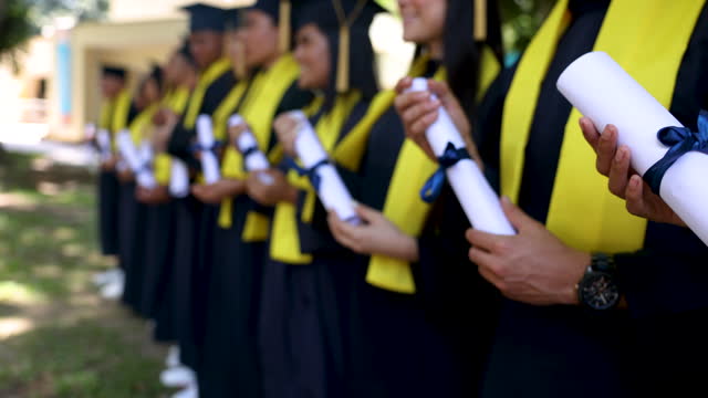 Group of graduates standing in a row holding their diplomas
