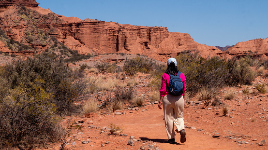 young woman hiking  in a dirt path near a few small hills in 