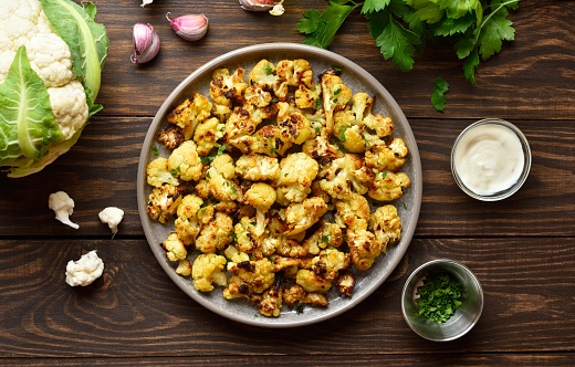 Roasted cauliflower on wooden background. Vegetarian vegan food concept. Top view, flat lay