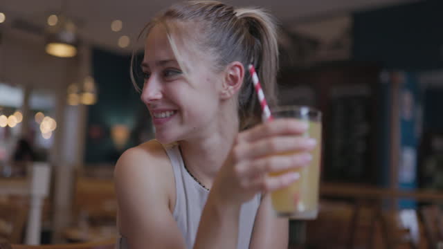 Teenage girl enjoying mixed juice and lemonade while waiting for the order in restaurant