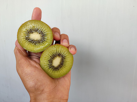 Photo of a hand holding a sliced kiwi fruit