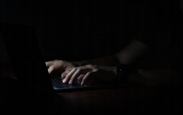 istock Close up of hands typing and using laptop in the dark. 1759843715