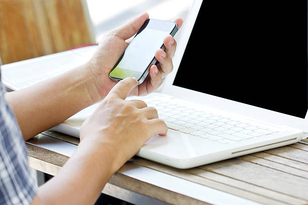 istock Smartphone in Asian man's hands over a white laptop. 175985929